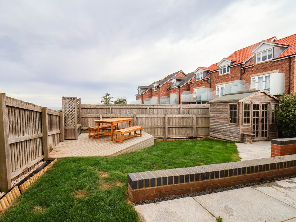A garden with a wooden table and benches at 64 Derwent Road in Whitby