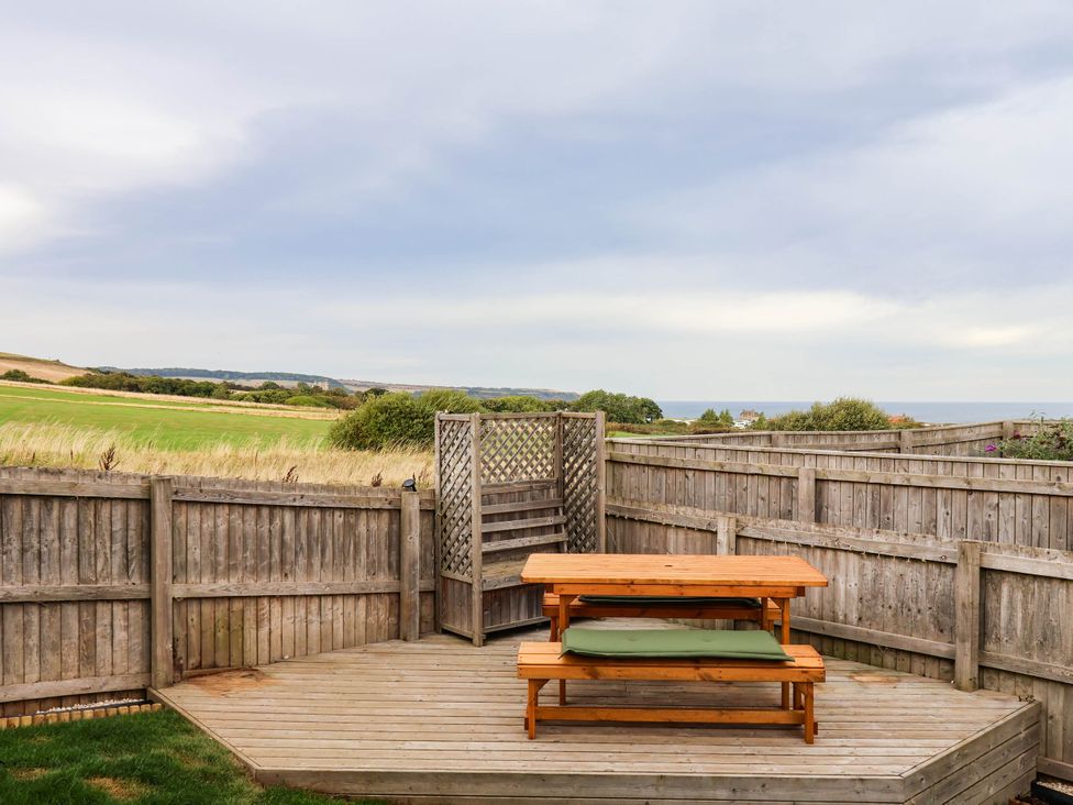 A deck with a wooden bench and fence at 64 Derwent Road in Whitby