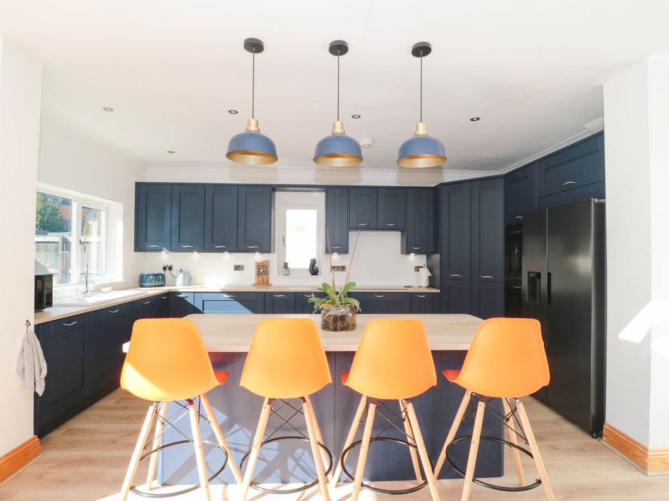 A kitchen with dark cabinets and orange bar stools at Ashbourne House