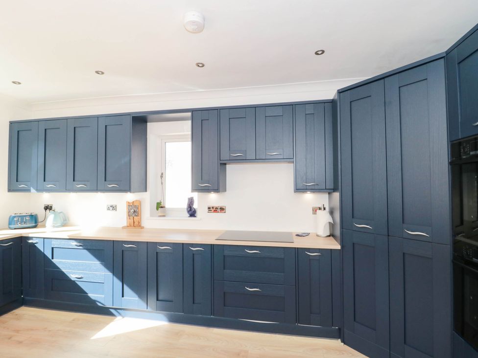 A kitchen with blue cabinets and appliances at Ashbourne House 