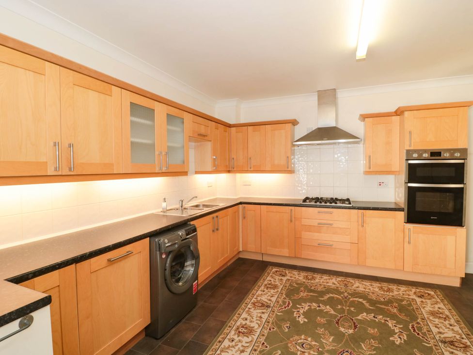 A kitchen with cabinets, sink, gas stove, and washing machine at Ashbourne House