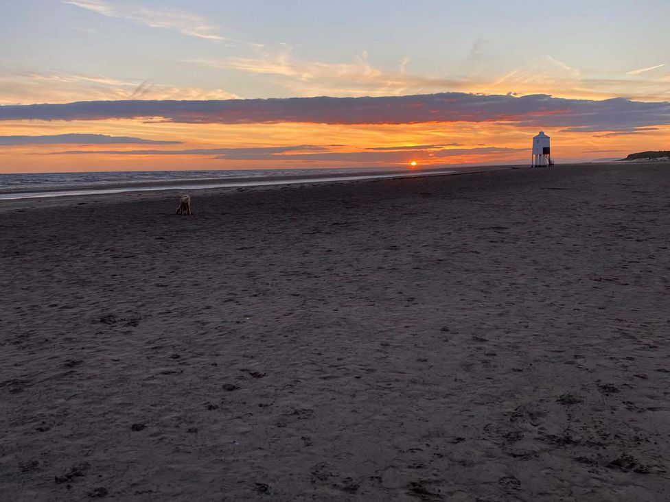 A beach with a lifeguard tower and a dog at sunset at Ashbourne House in Burnham-On-Sea