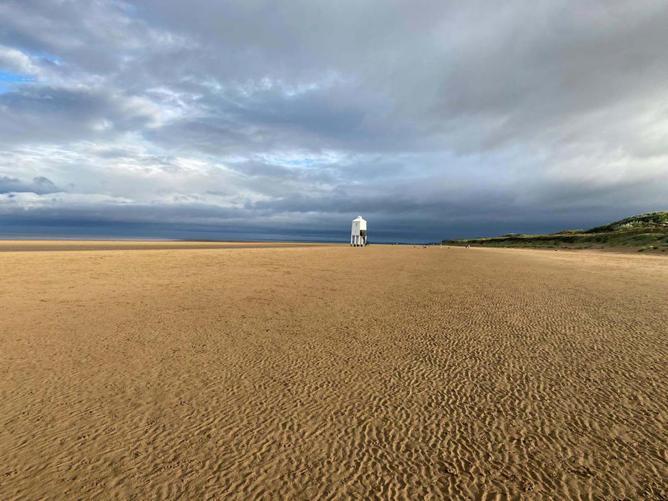 A beach with a lighthouse and cloudy sky at Ashbourne House in Burnham-On-Sea