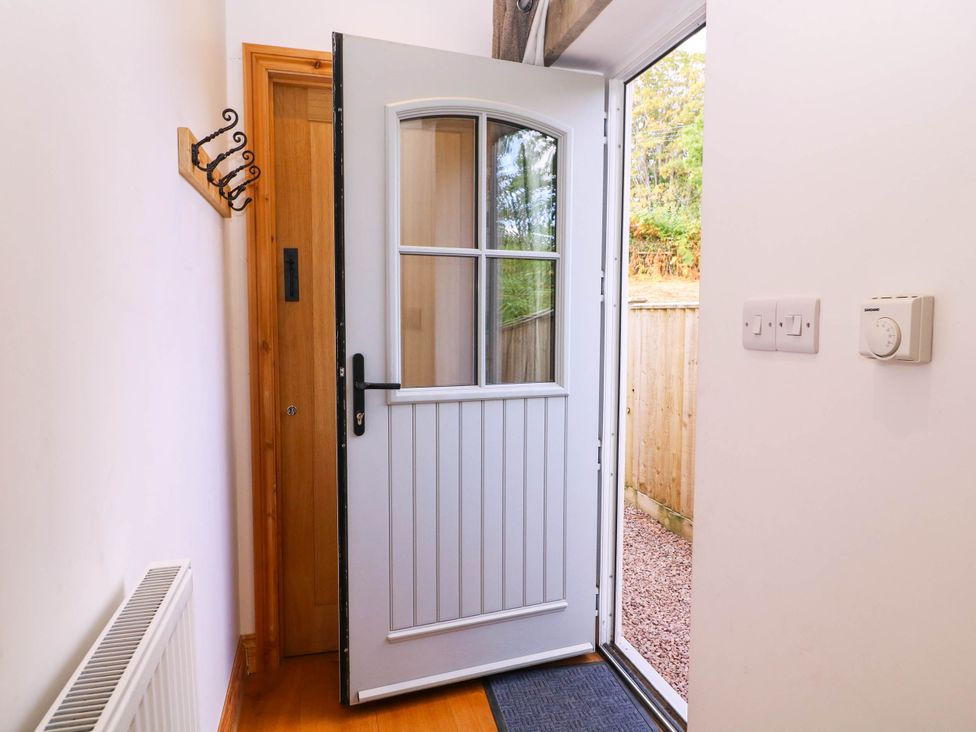 An entrance hall with a door and coat hooks at The Burrow at Aveling Cottage in Lydney