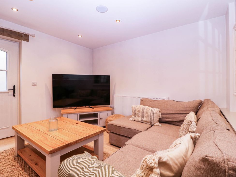 A living room with a sofa and television at The burrow at Aveling Cottage in Lydney