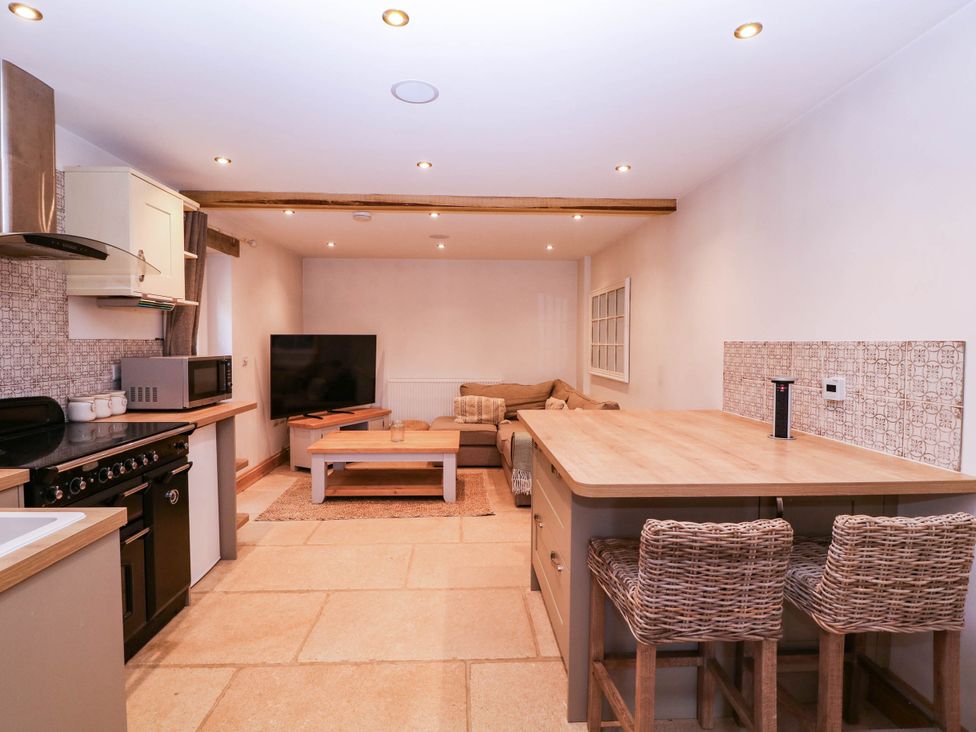 A kitchen with a sofa and television at The burrow at Aveling Cottage in Lydney