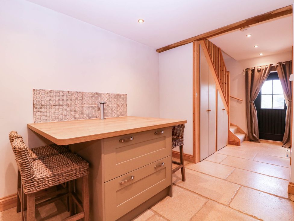 A kitchen with island and bar stools at The burrow at Aveling Cottage Lydney