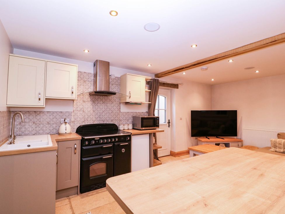 A kitchen with a sink stove and television at The burrow at Aveling Cottage in Lydney