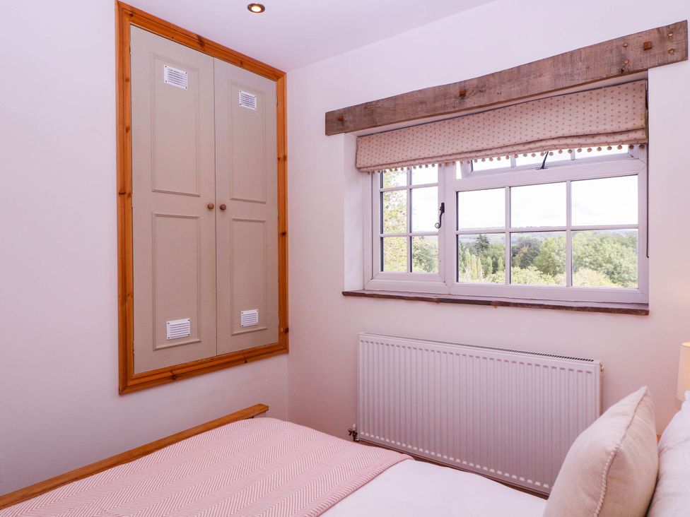 A bedroom with a bed and a window at The Burrow at Aveling Cottage in Lydney