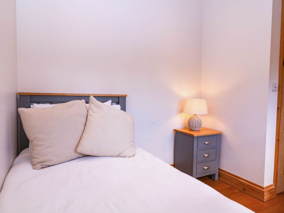 A bedroom with a bed and bedside table lamp at The burrow at Aveling Cottage Lydney