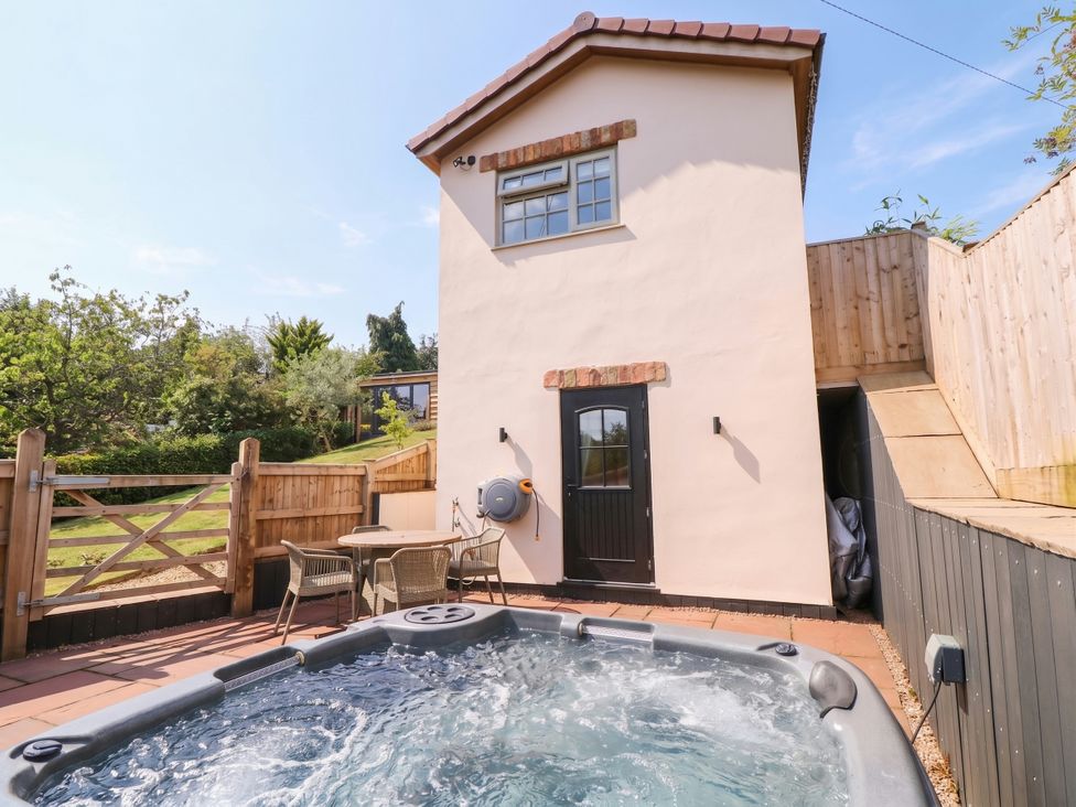 An outdoor area with a hot tub and seating at The Burrow at Aveling Cottage in Lydney