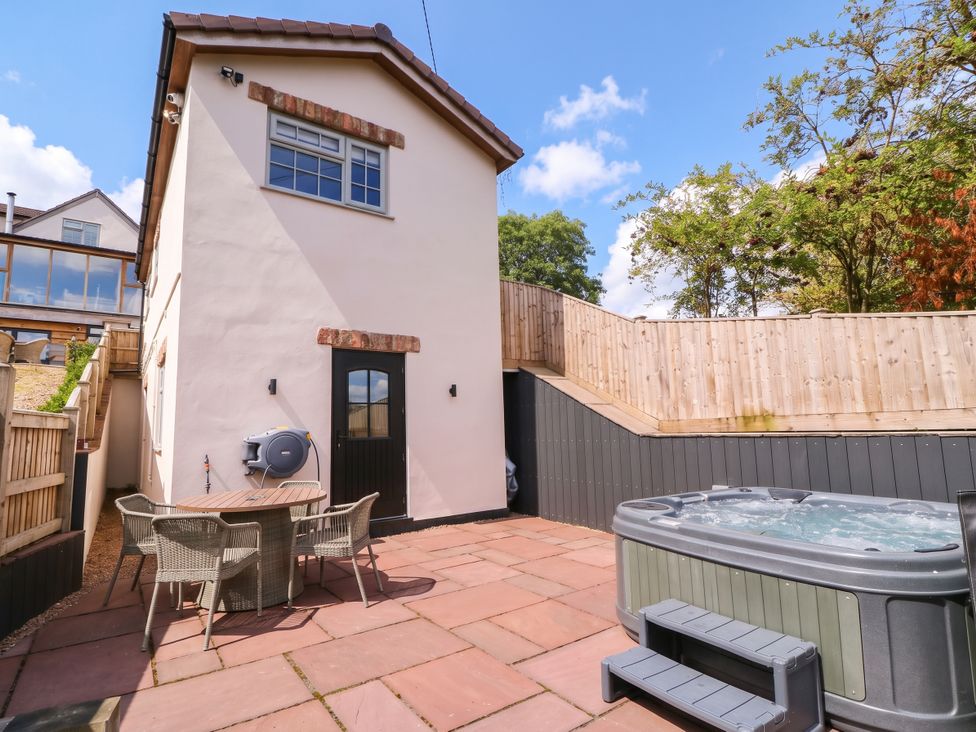 An outdoor area with a hot tub and table at The Burrow at Aveling Cottage Lydney
