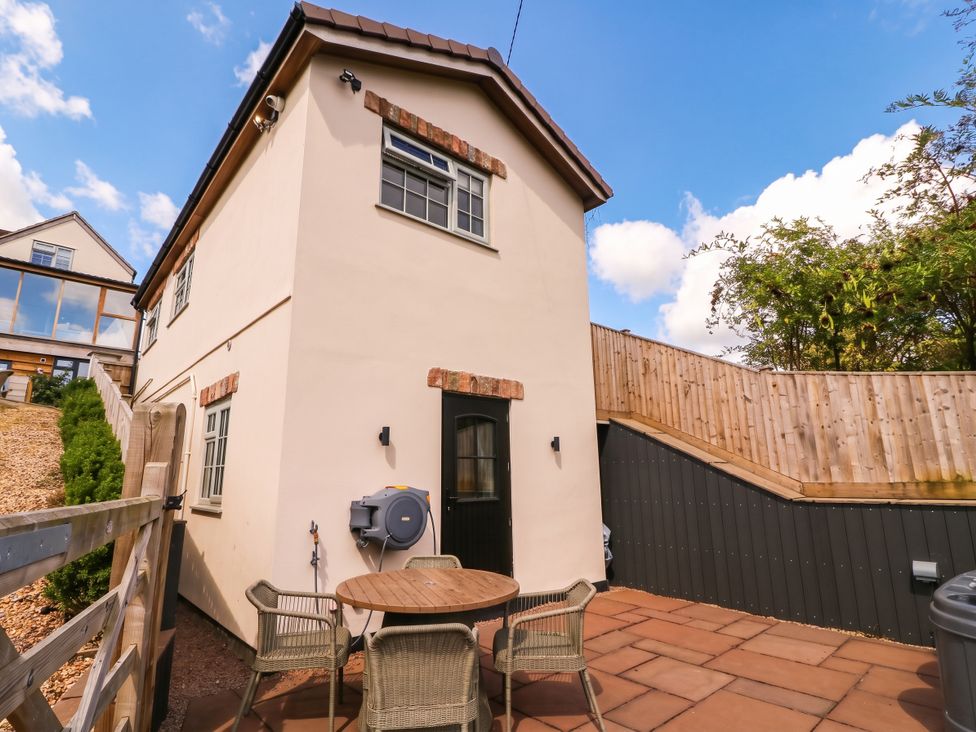 An outdoor view of a house with a table and chairs at The Burrow at Aveling Cottage in Lydney