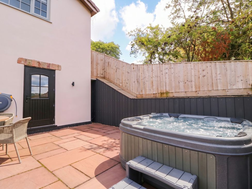 An outdoor area with a hot tub and seating at The Burrow at Aveling Cottage in Lydney