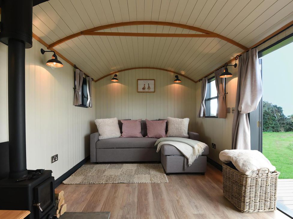 A snug area with a sofa and wood stove at Shepherd Hut at Garden Cottage near Woolaston