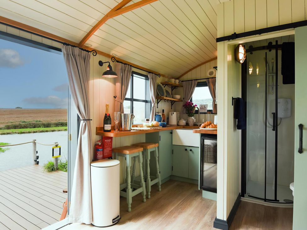A kitchen with a counter and bar stools at Shepherd Hut at Garden Cottage near Woolaston
