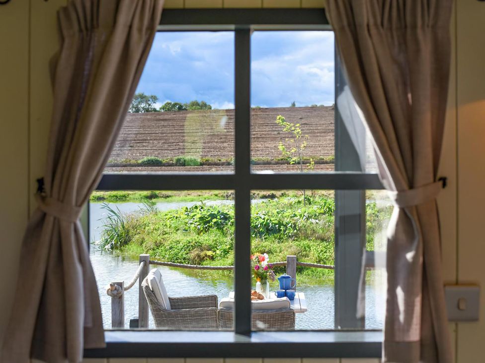 A view of a table and chairs by the water at Shepherd Hut at Garden Cottage near Woolaston