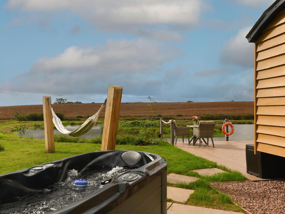 An outdoor area with a hot tub and hammock at Shepherd Hut at Garden Cottage near Woolaston