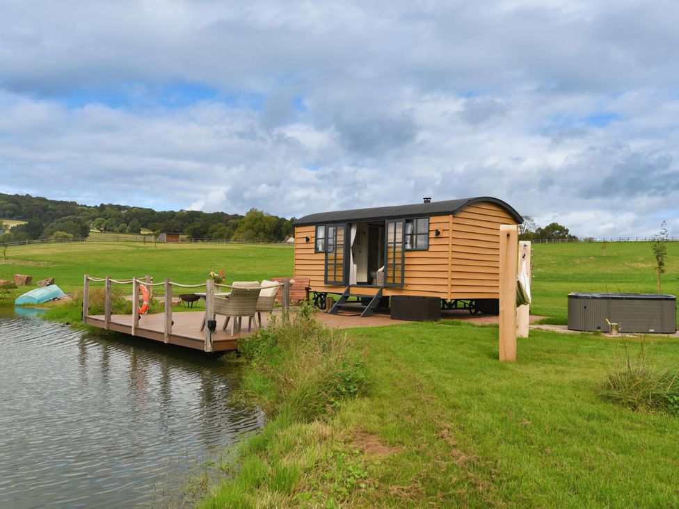 A shepherd hut beside a pond at Shepherd Hut at Garden Cottage near Woolaston