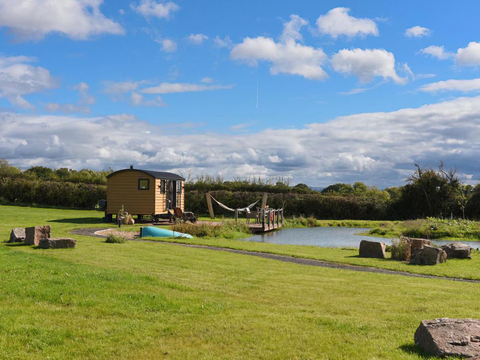 A hut and pond with a deck at Shepherd Hut at Garden Cottage near Woolaston
