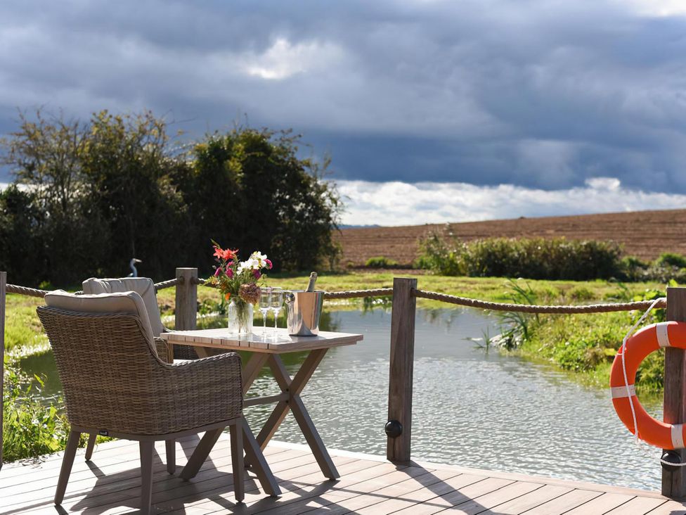 A table with flowers and drinks beside a river at Shepherd Hut at Garden Cottage near Woolaston