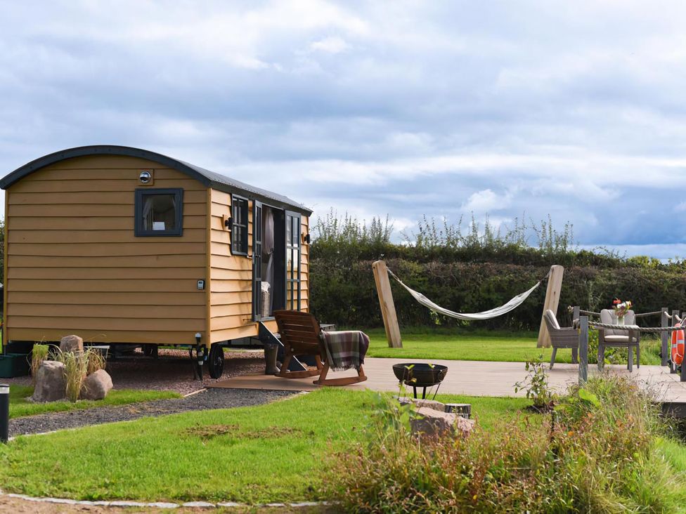 A shepherd hut with hammock and seating area at Shepherd Hut at Garden Cottage near Woolaston