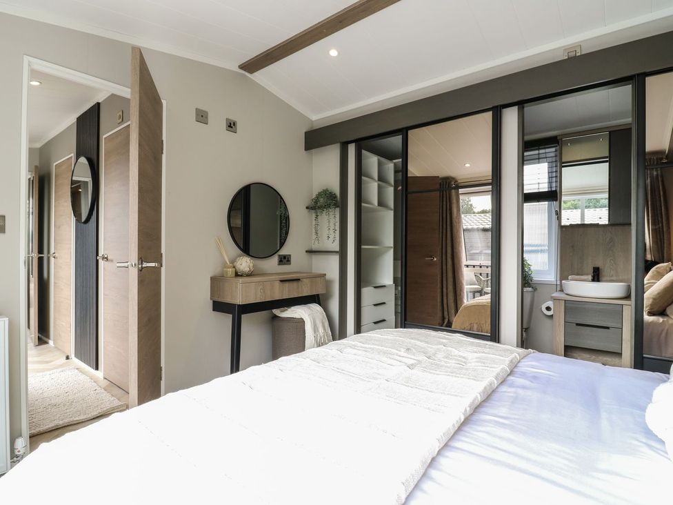 A bedroom with a bed and a mirror at Lakewood Plot 7 Clacton-on-Sea