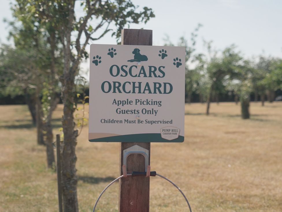 A sign indicating Oscars Orchard for apple picking at Pump Hill Caravan Park