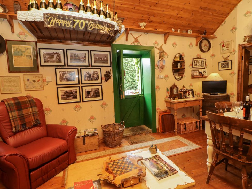 A living room with a green door and photographs on the wall at Teresa's Cottage