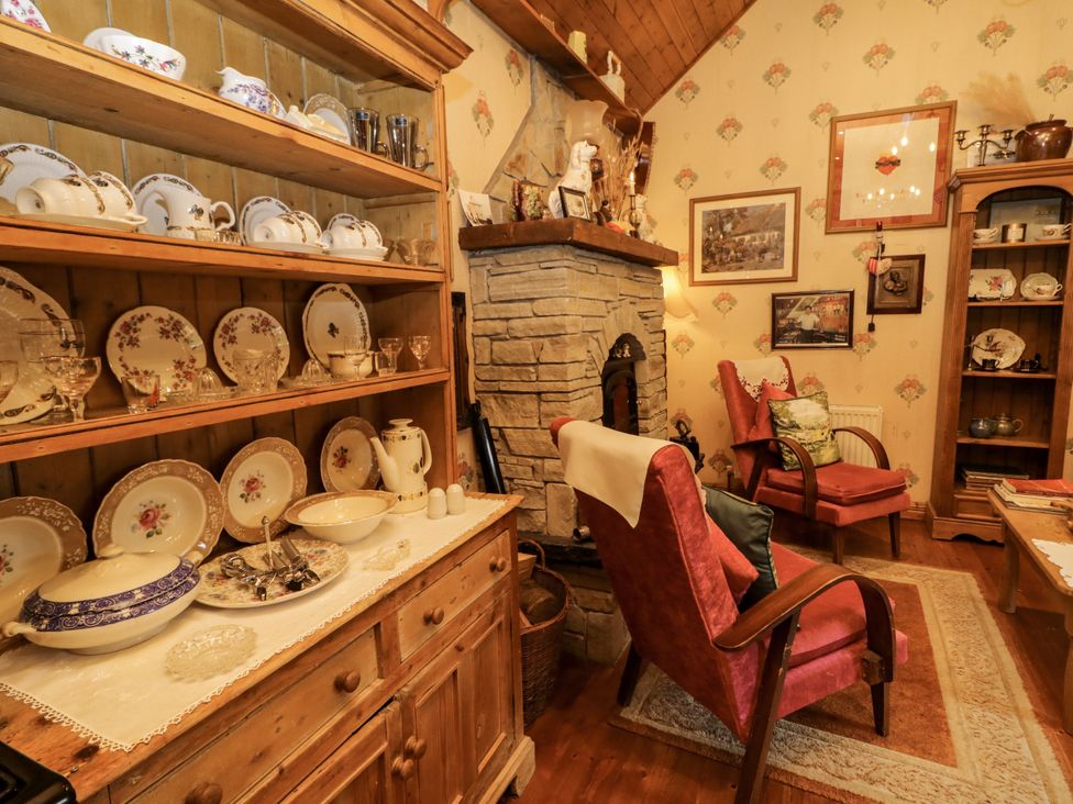 A living room with shelves displaying dishes and a fireplace at Teresa's Cottage