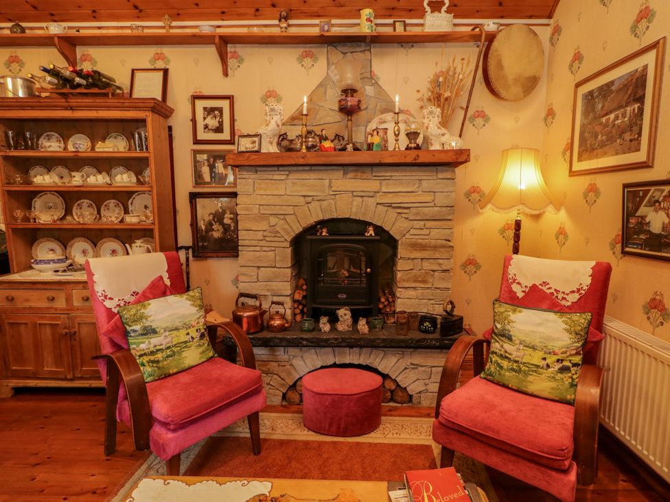 A living room with a fireplace and wooden shelves at Teresa's Cottage