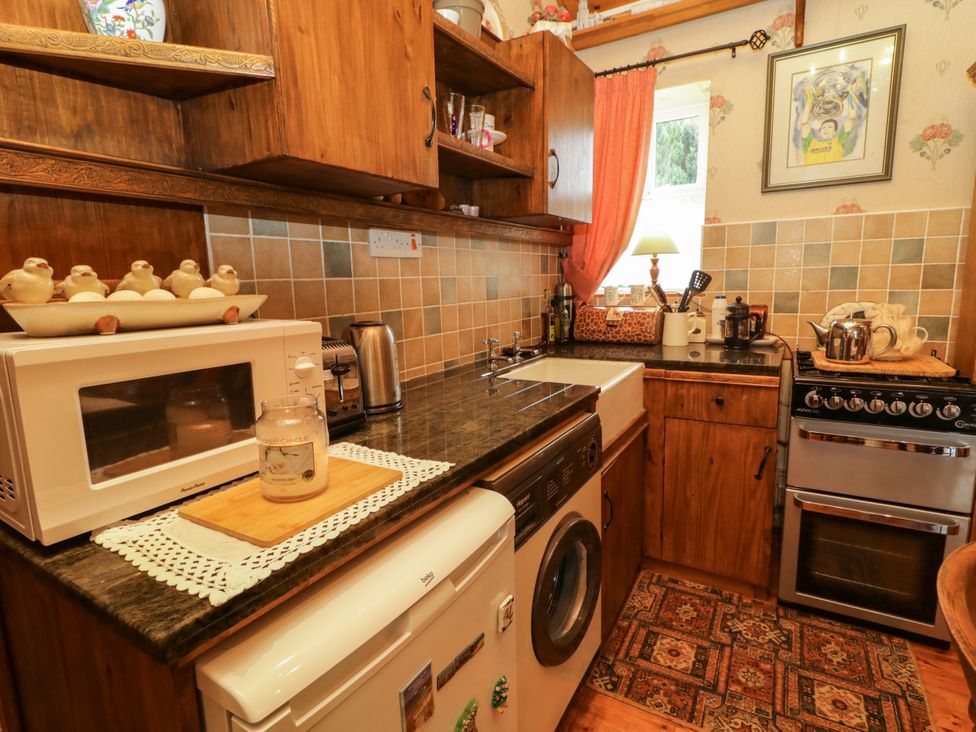 A kitchen with a washing machine and microwave at Teresa's Cottage