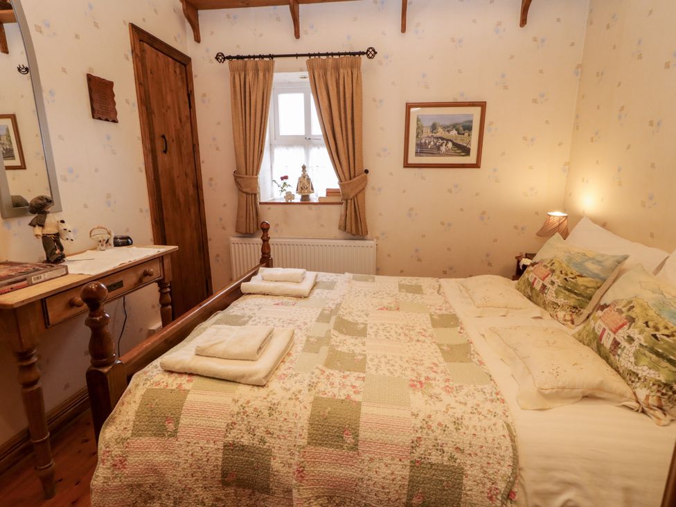 A bedroom with a bed, mirror, and window at Teresa's Cottage