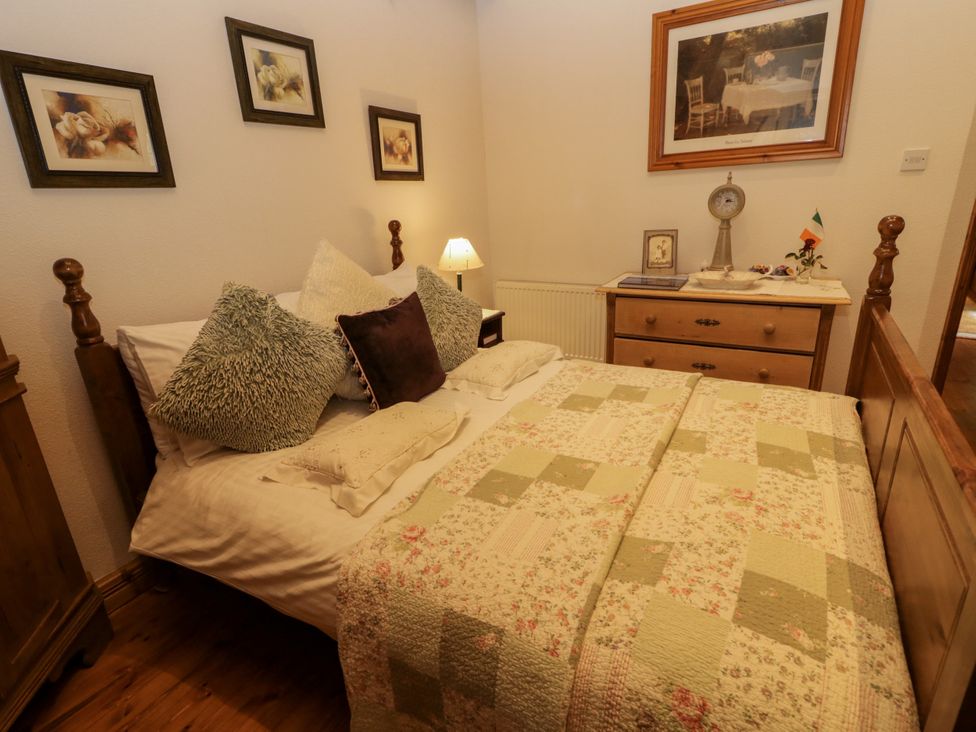 A bedroom with a bed, pillows and wall art at Teresa's Cottage