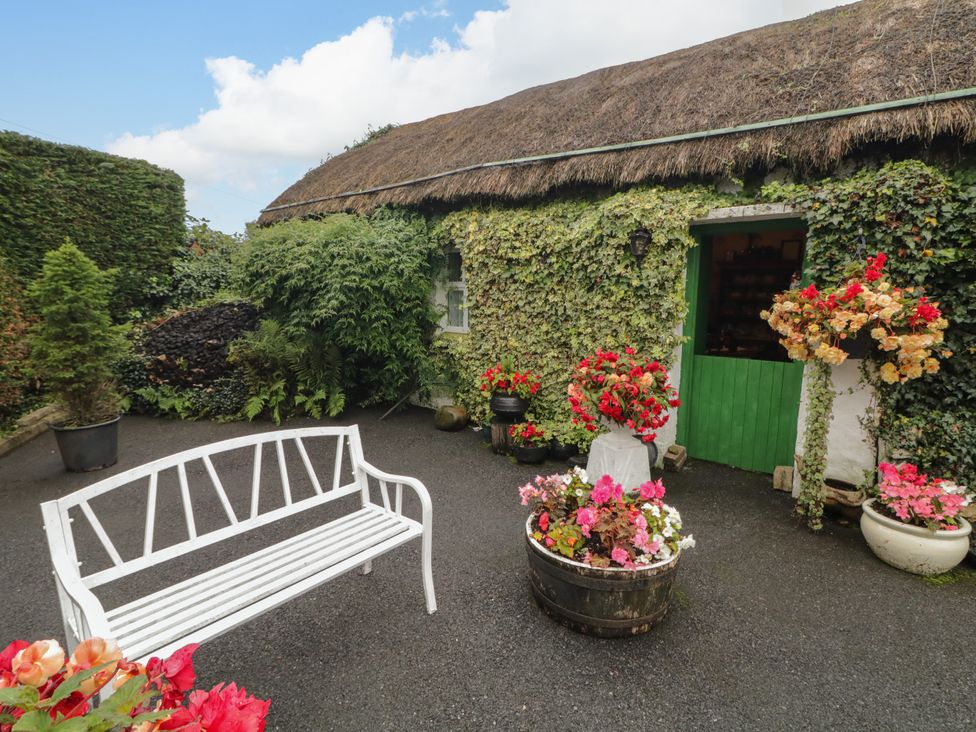 A garden with a white bench and flower pots at Teresa's Cottage