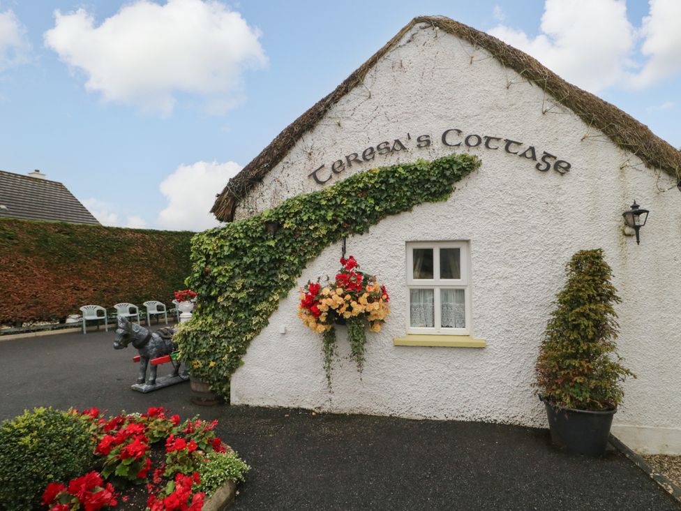 An exterior view of Teresa's Cottage with flowers and a horse statue in a garden