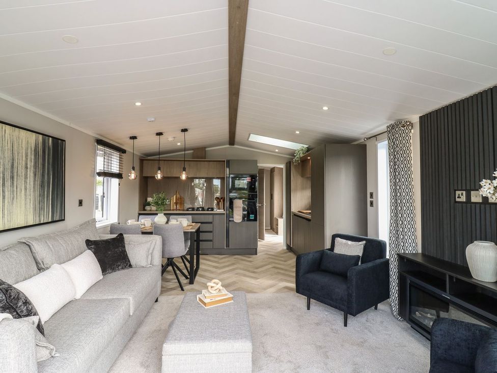 A living room with a kitchen area featuring a sofa and dining table at Lakewood Plot 8
