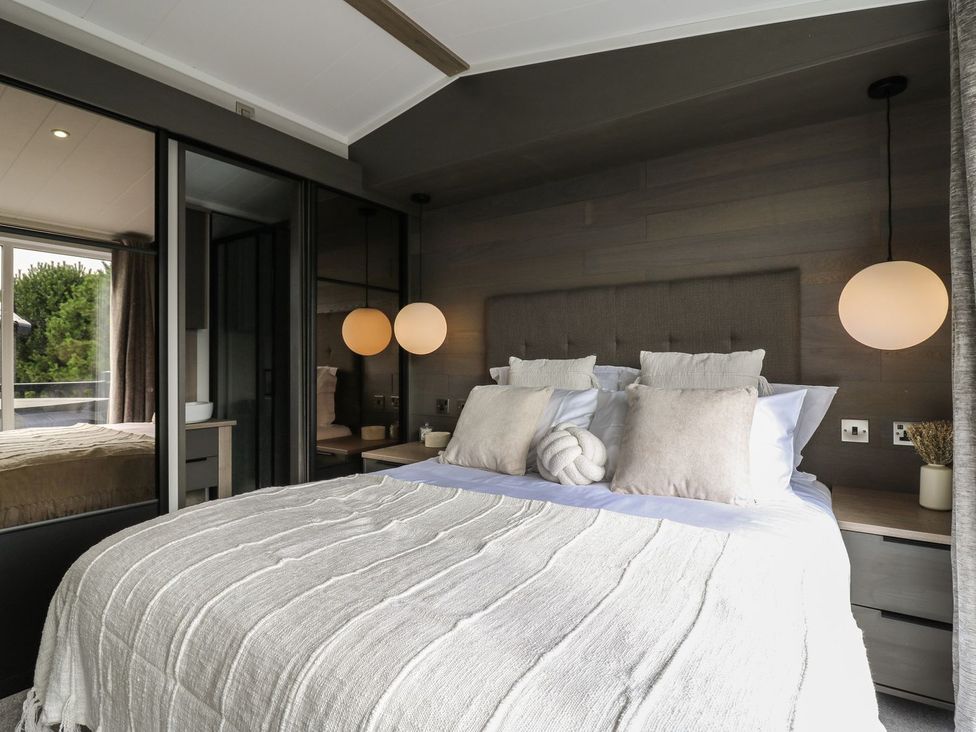 A bedroom with a bed and large window at Lakewood Plot 8 