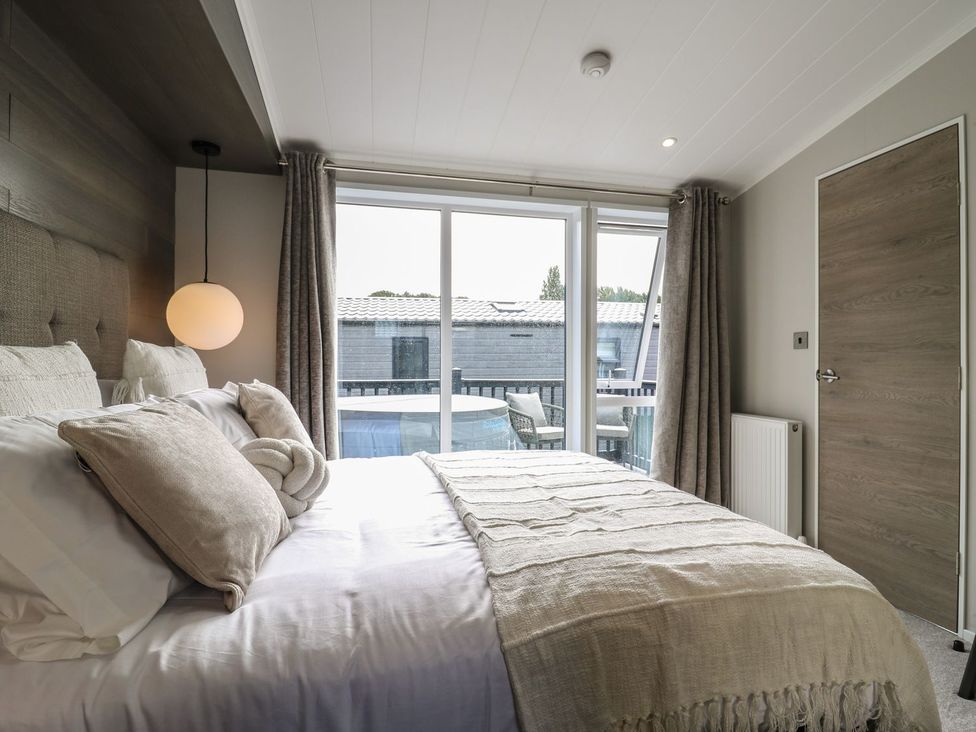 A bedroom with a bed and large window at Lakewood Plot 8