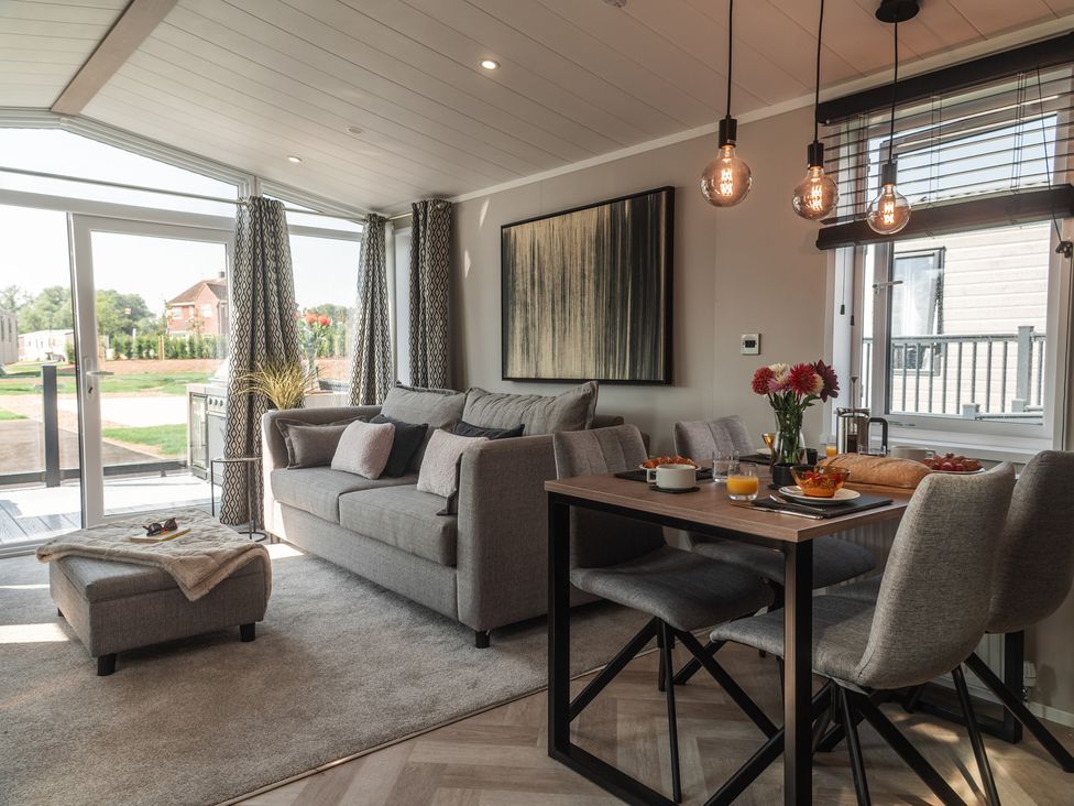 A living room with a sofa and dining area at Lakewood Plot 8 St. Osyth