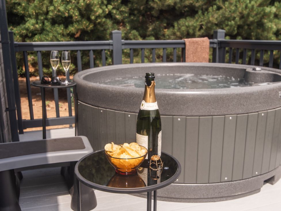 An outdoor area with a hot tub and a table with snacks at Lakewood Plot 8 St. Osyth