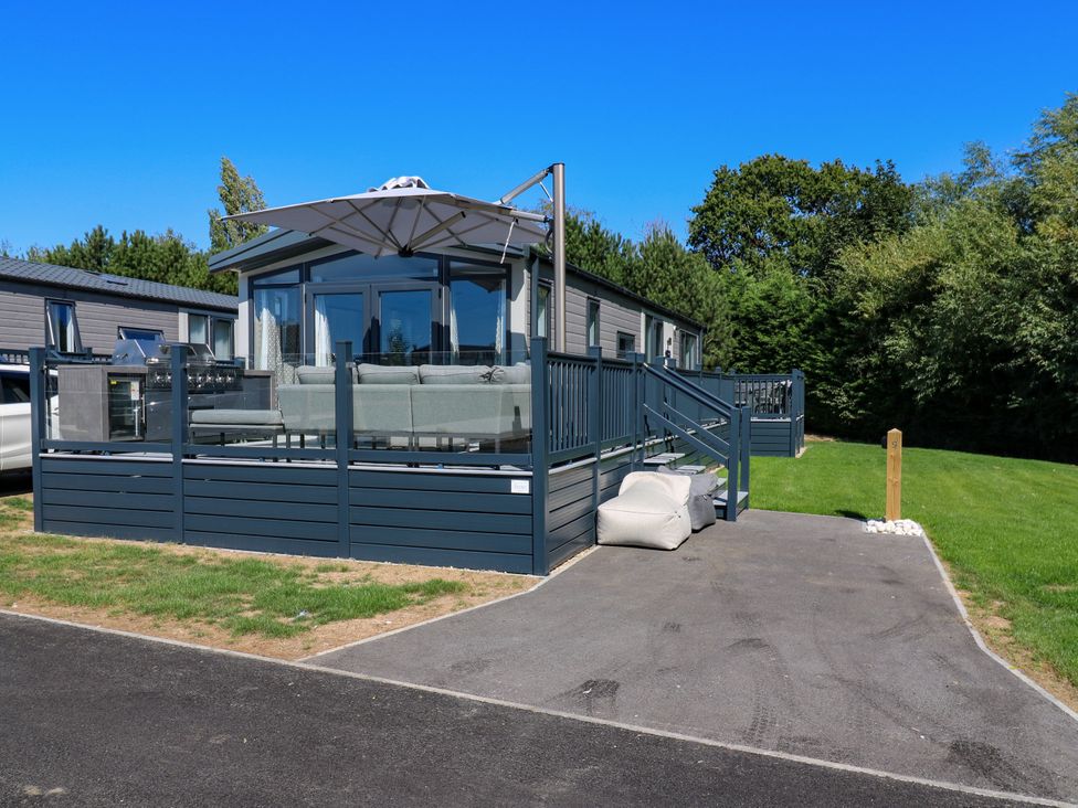 An outdoor area with a deck, sofa, and parasol at Lakewood Plot 9 in St. Osyth