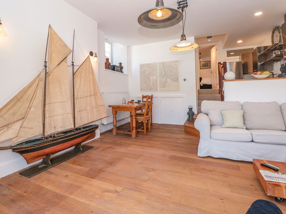 A living room with a ship model and dining table at Shipwrights in Brixham