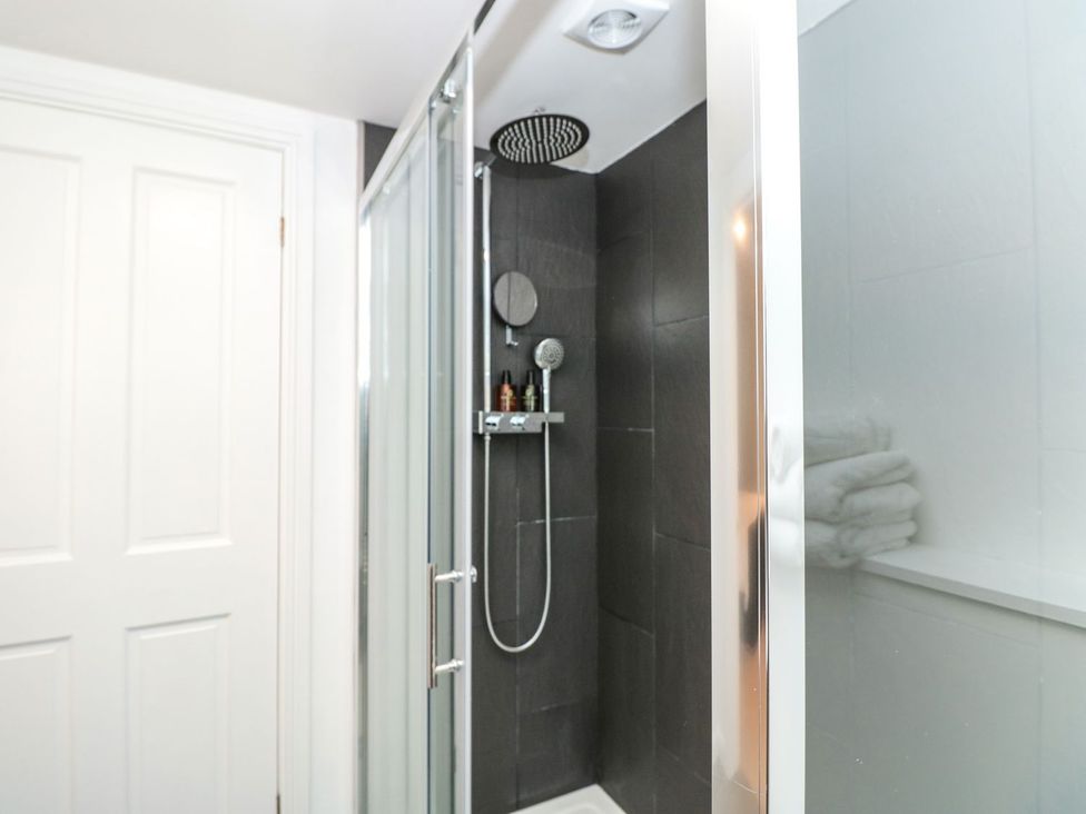 A shower with glass doors and a towel shelf at Shipwrights in Brixham