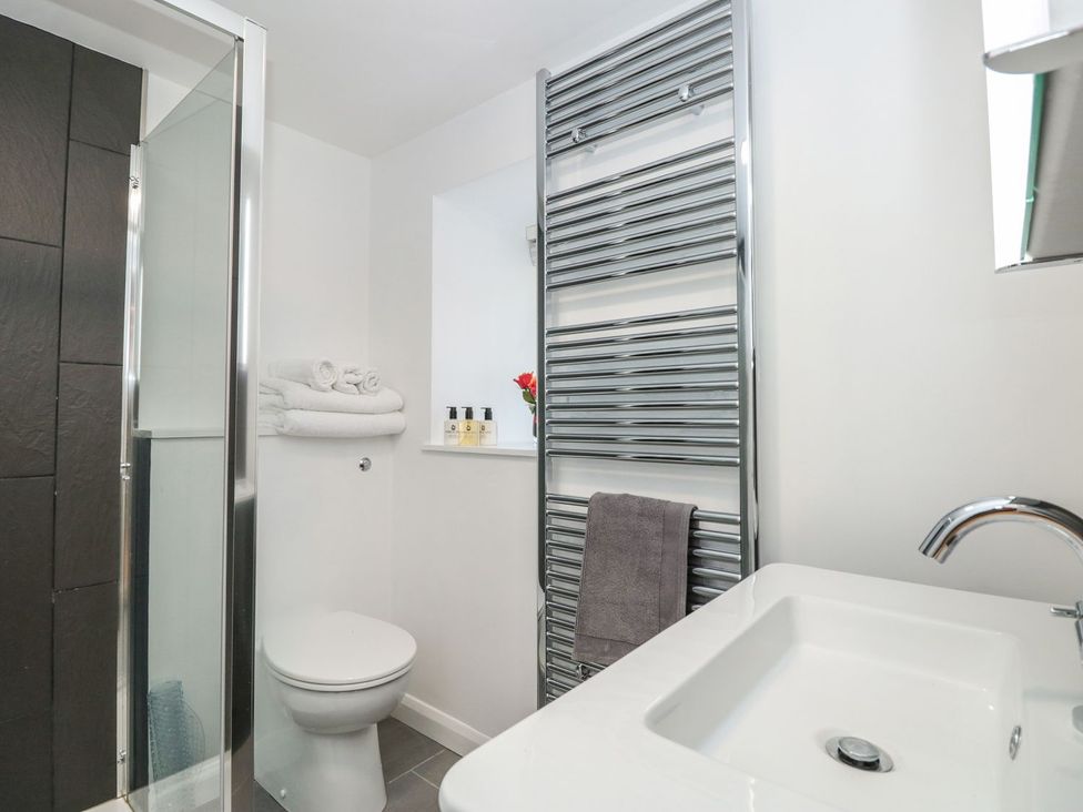 A bathroom featuring a shower, toilet, sink and towels at Shipwrights in Brixham