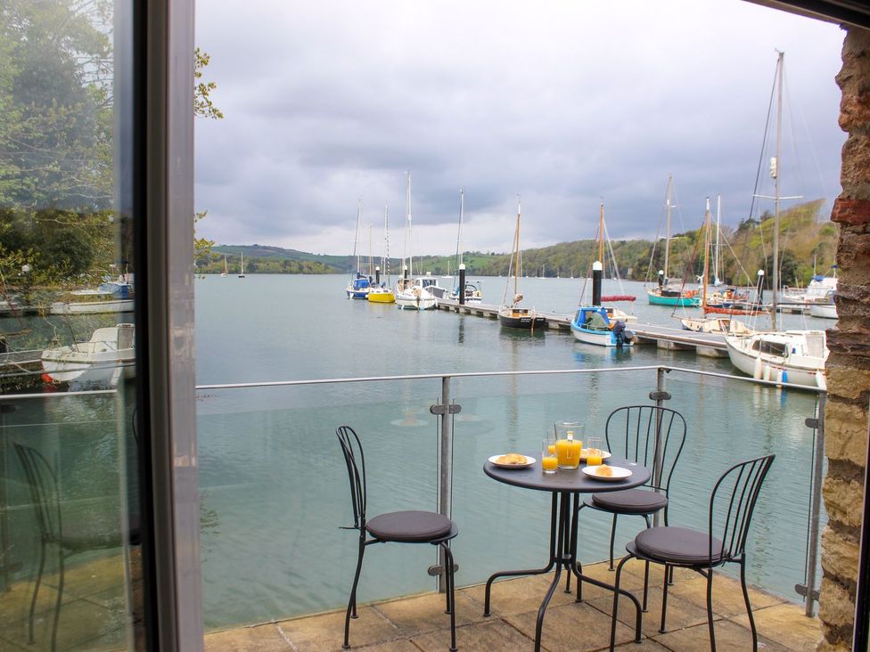 A patio with a table and chairs overlooking a harbor at Spanish Boathouse in Brixham