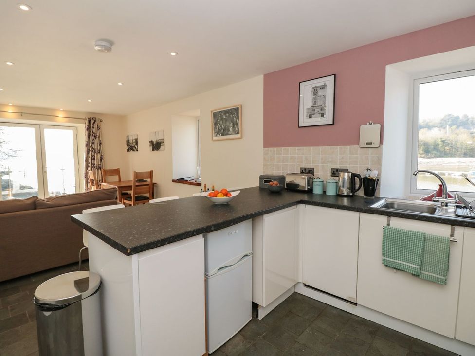 A kitchen with an island, sink, and chairs at Spanish Boathouse in Brixham