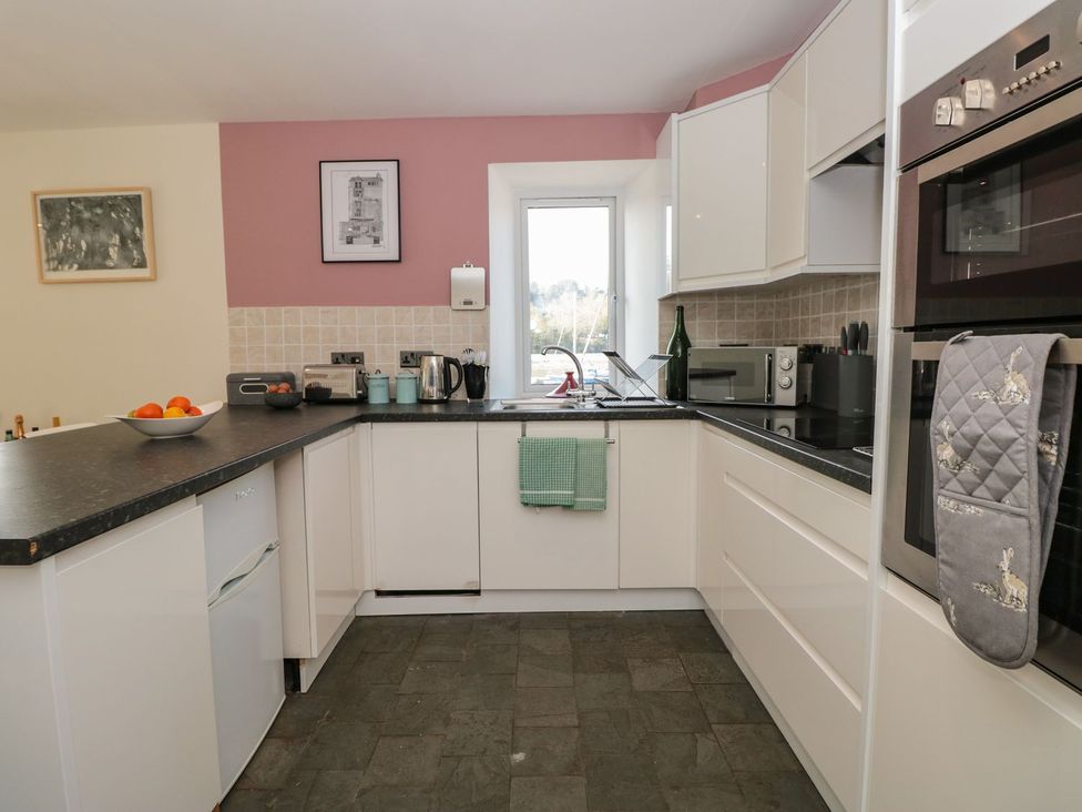 A kitchen with a sink, oven, and window at Spanish Boathouse in Brixham
