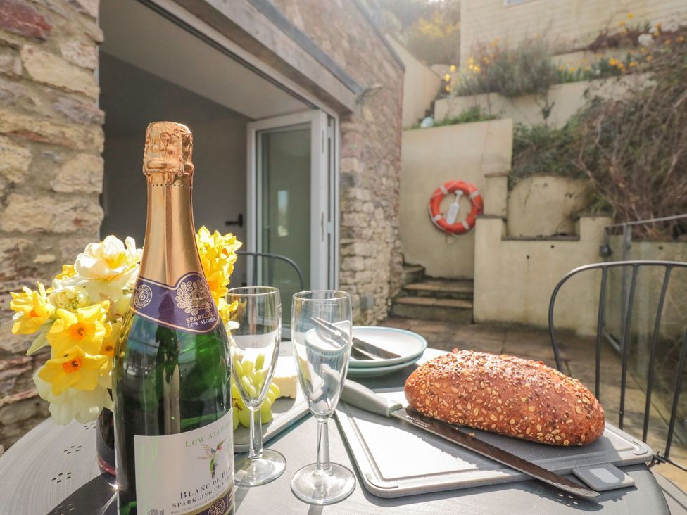 An outdoor dining table with champagne, glasses, and bread at Spanish Boathouse in Brixham