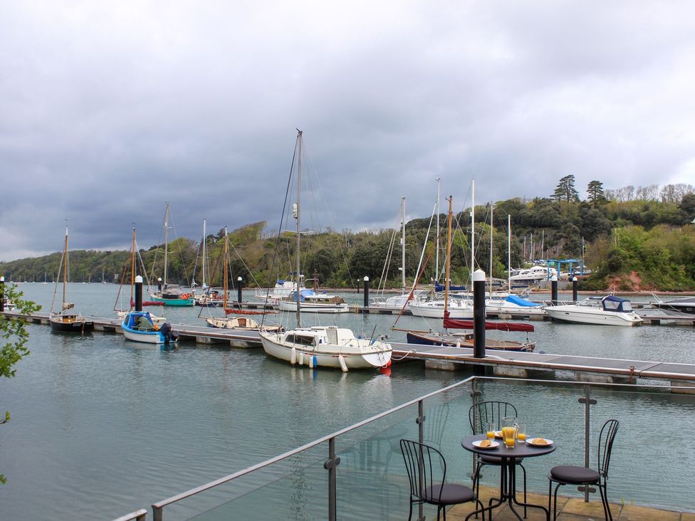 An outdoor area with a table and chairs overlooking boats at Spanish Boathouse Brixham
